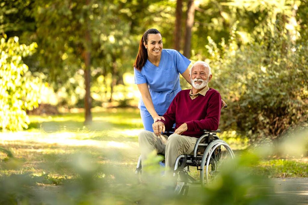An older adult and a caregiver discussing a care plan together at a dining table, with paperwork and pens visible.